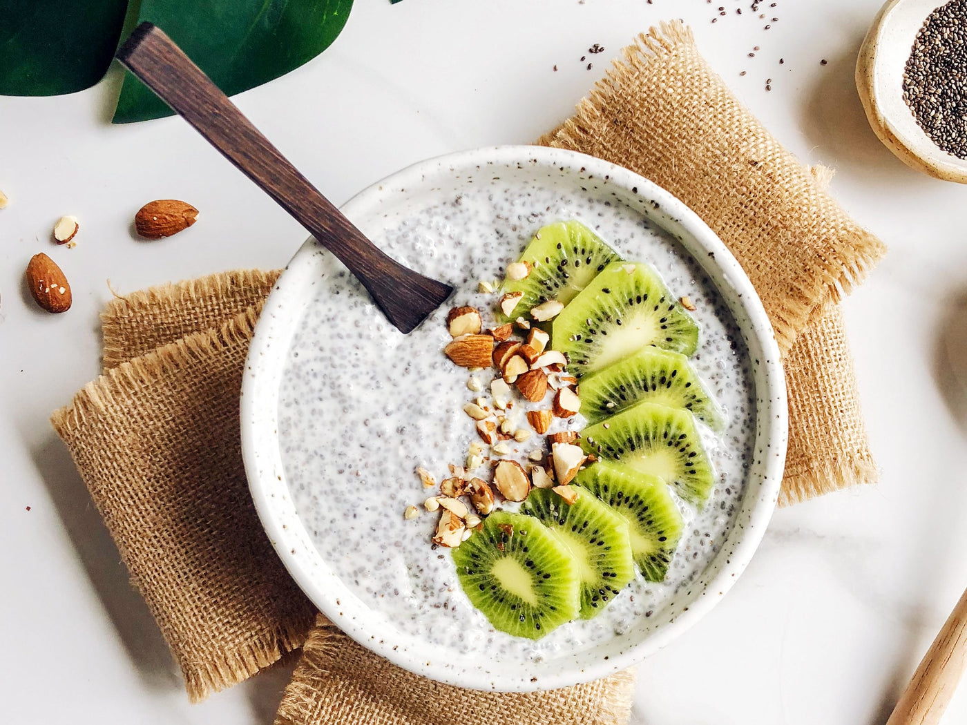 Chia seed pudding from Sophie Guidolin recipes with kiwi and crushed nuts in a white bowl