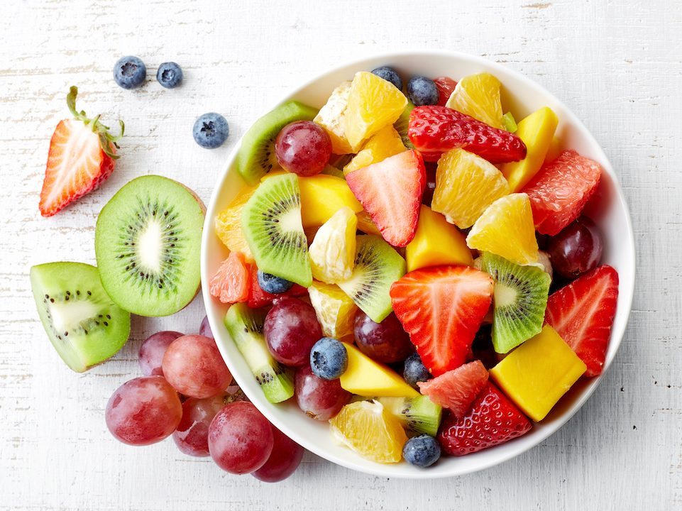 Bowl of healthy fresh fruit salad on wooden background