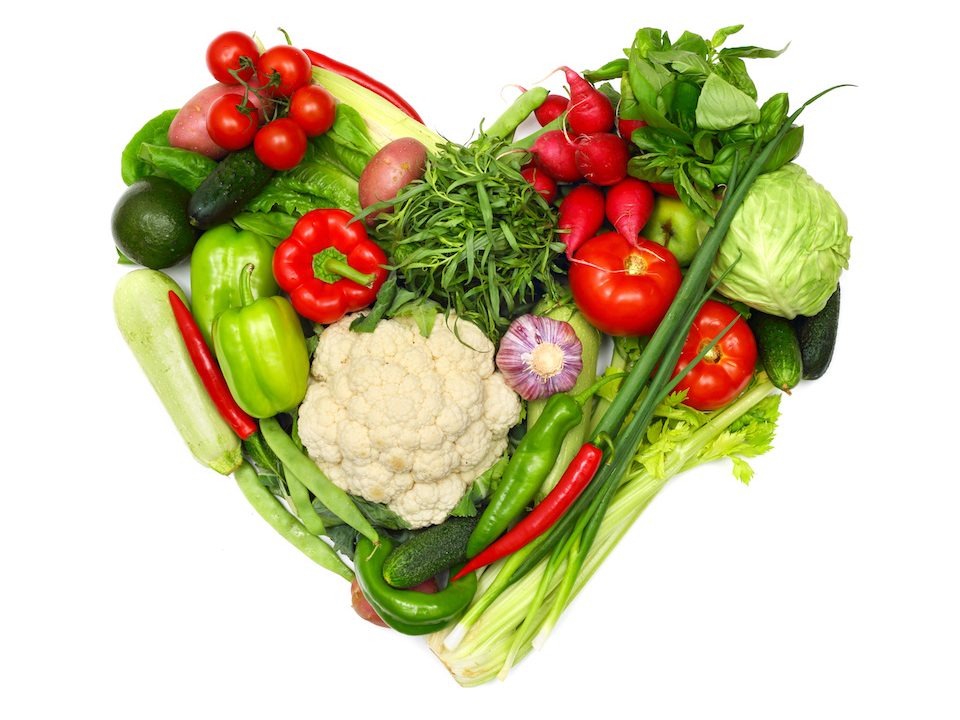 Pile of vegetables shaped as heart isolated on white background