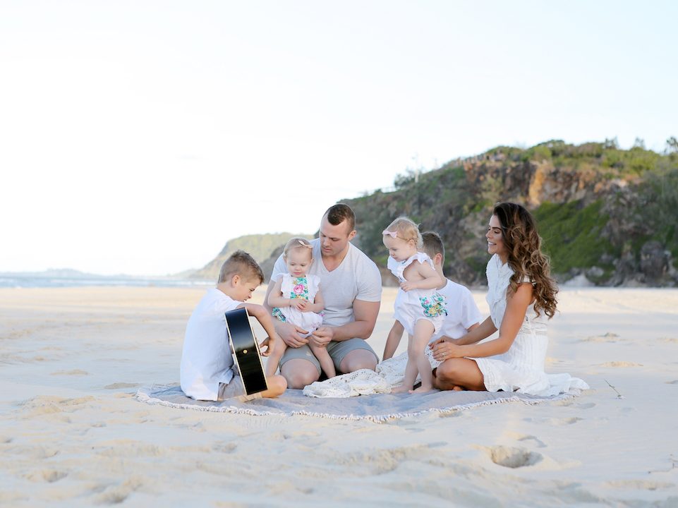 Four kids and parents at the beach wearing white|