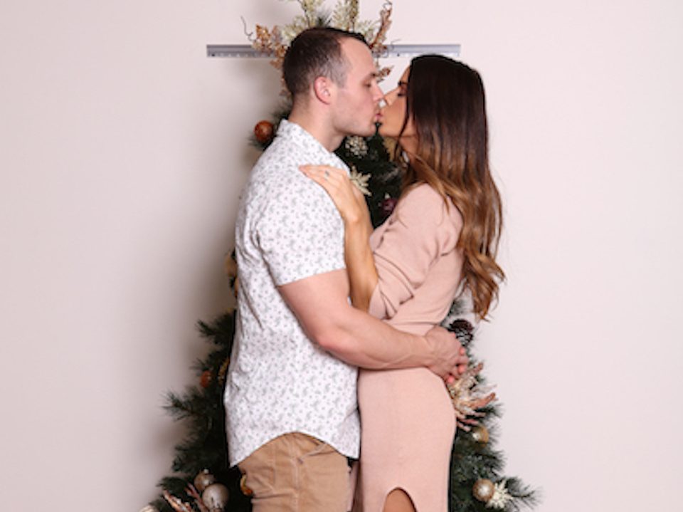 Sophie Guidolin and Nathan Wallace kissing in front of a Christmas tree