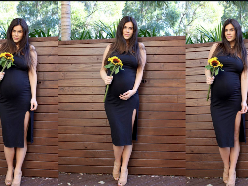 Sophie Guidolin twin pregnancy photo wearing a black dress and holding a sunflower